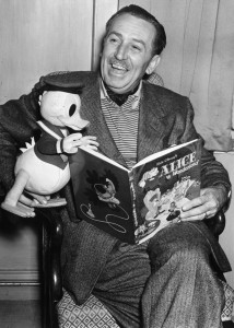 22nd June 1951:  Creator of Mickey Mouse Walt Disney (1901-1966) arrives in London to see the premiere of his latest film.  He holds a model of his character Donald Duck whilst looking at a copy of the Walt Disney book of the new film 'Alice In Wonderland'.  (Photo by Edward G. Malindine/Topical Press Agency/Getty Images)