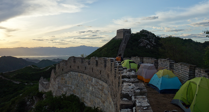 Alcuni viaggiatori dormono in tenda lungo la Grande Muraglia Cinese. Photo Credits.